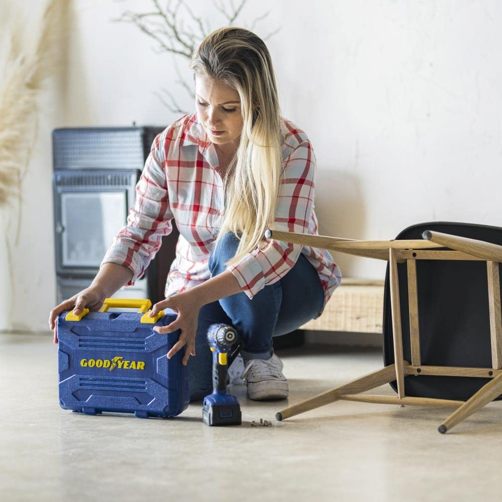 Mujer montando una silla con un taladro Goodyear. Herramientas y muebles en el suelo.