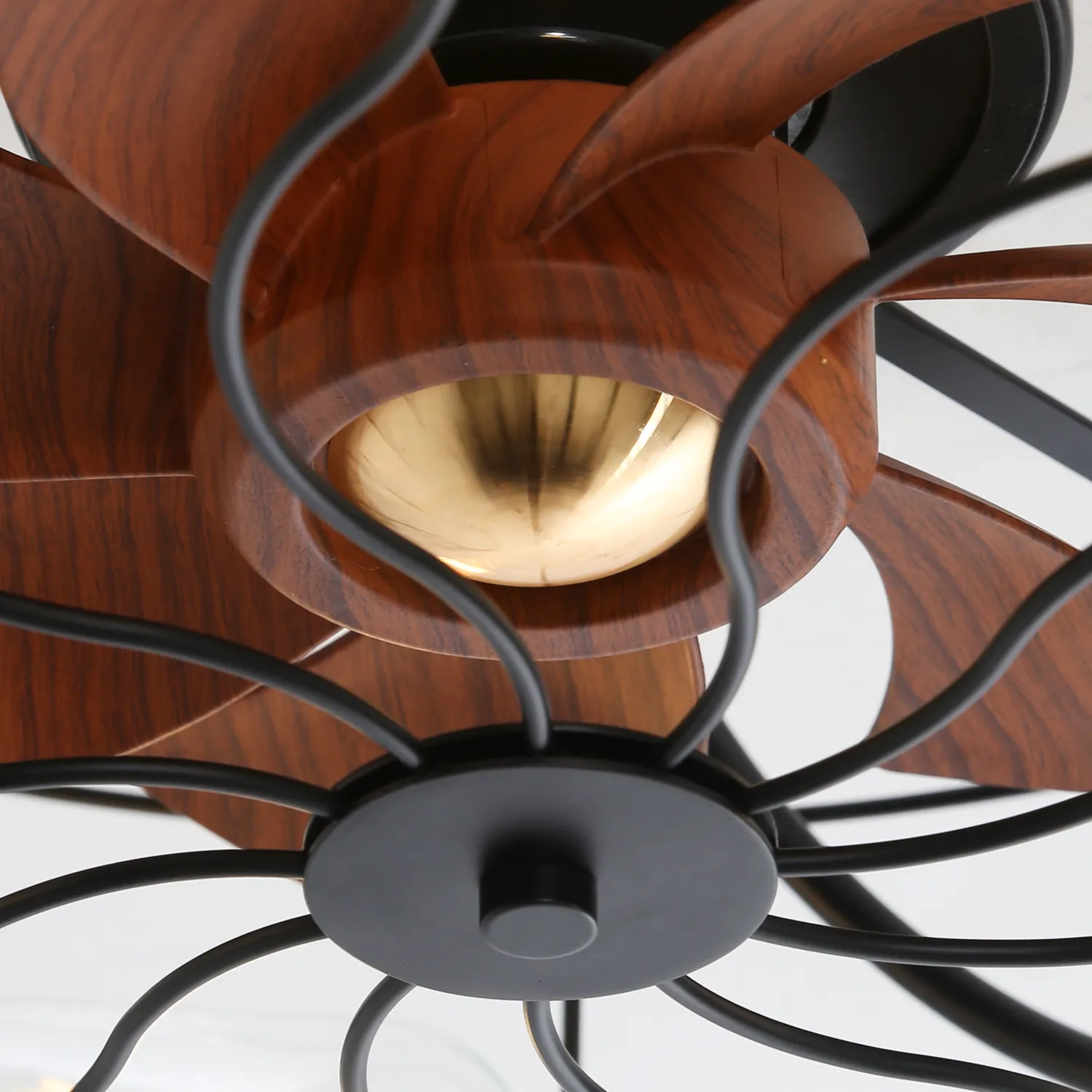 Deckenventilator, dunkle Holzblätter, schwarzer Metallrahmen, goldfarbene Mitte.