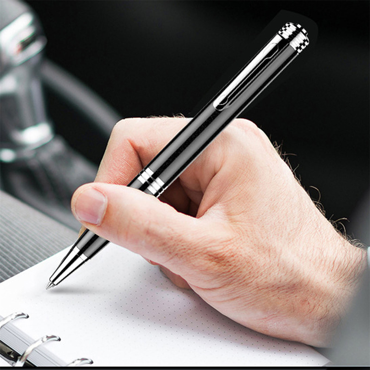 Eine Hand, die einen schwarzen Stift hält, schreibt in einem Auto auf einen weißen Notizblock.