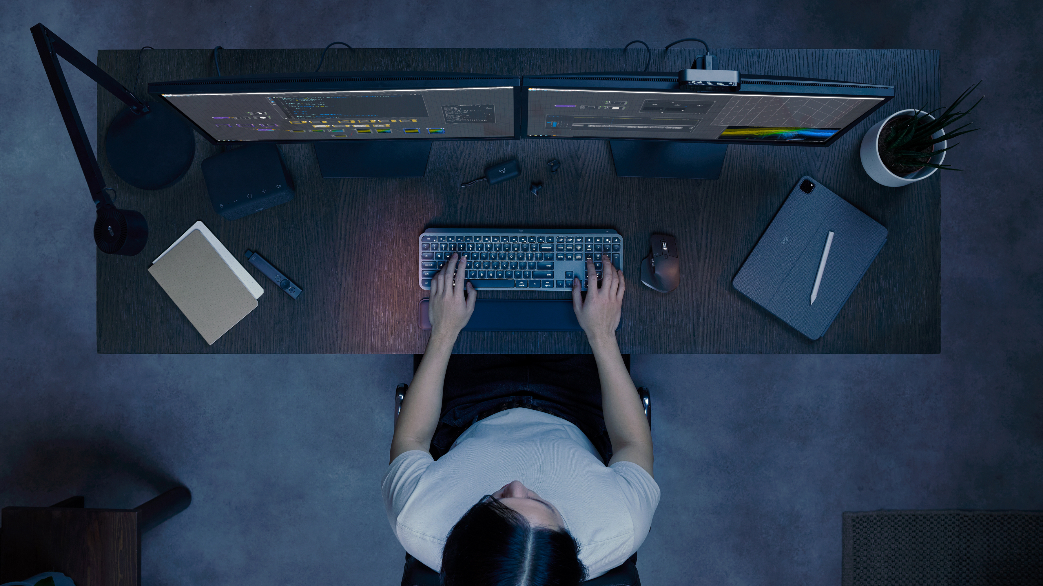 Widok z góry na osobę pracującą przy biurku z dwoma monitorami, klawiaturą i myszą.