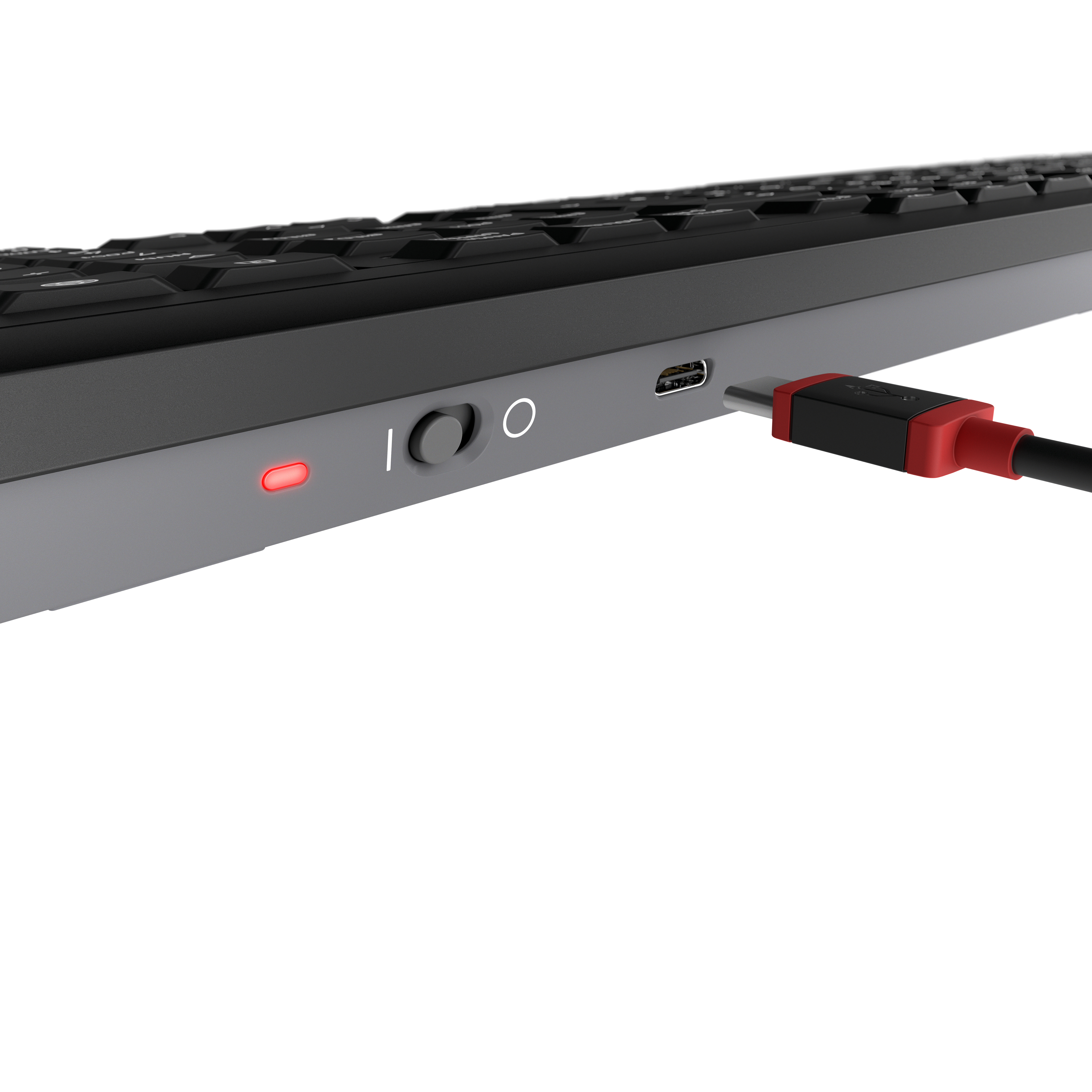 Primer plano de un teclado con un cable de carga rojo enchufado. El botón de encendido está iluminado.