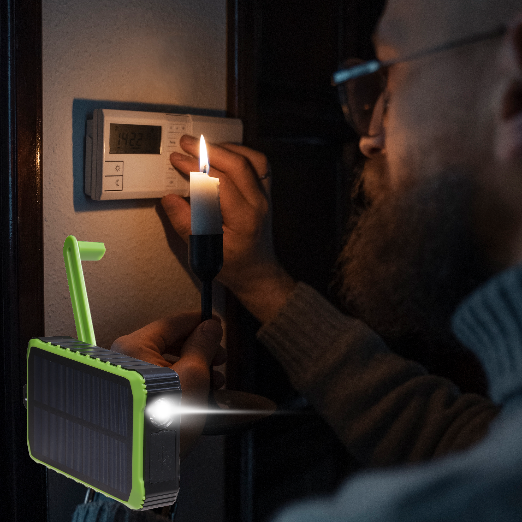 Une personne tenant une bougie et une lampe verte à énergie solaire dans une pièce sombre.