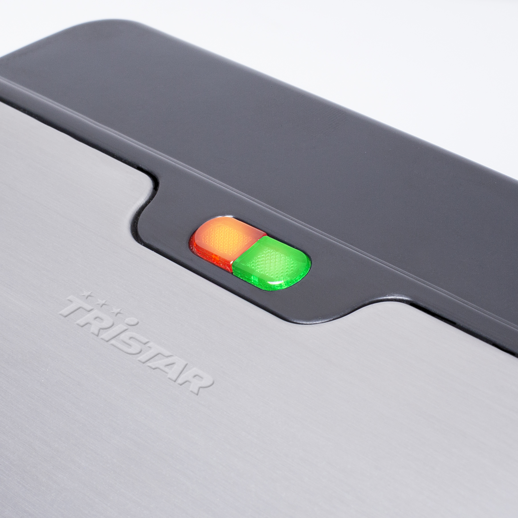 Zbliżenie srebrnego urządzenia z zielonymi i pomarańczowymi światłami, na białym tle.