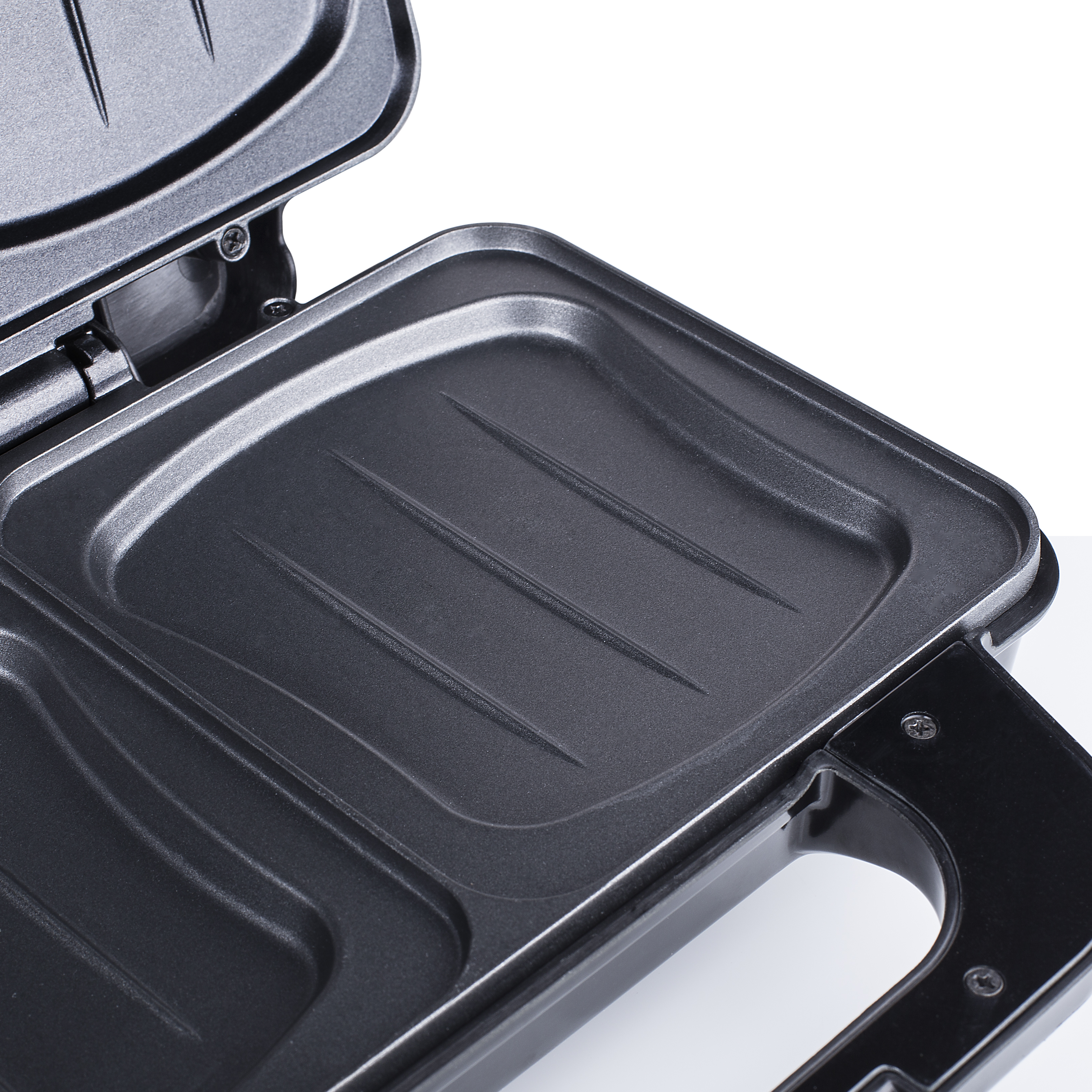 Zbliżenie wnętrza czarnego opiekacza do kanapek, pokazujące płyty grzewcze, białe tło.