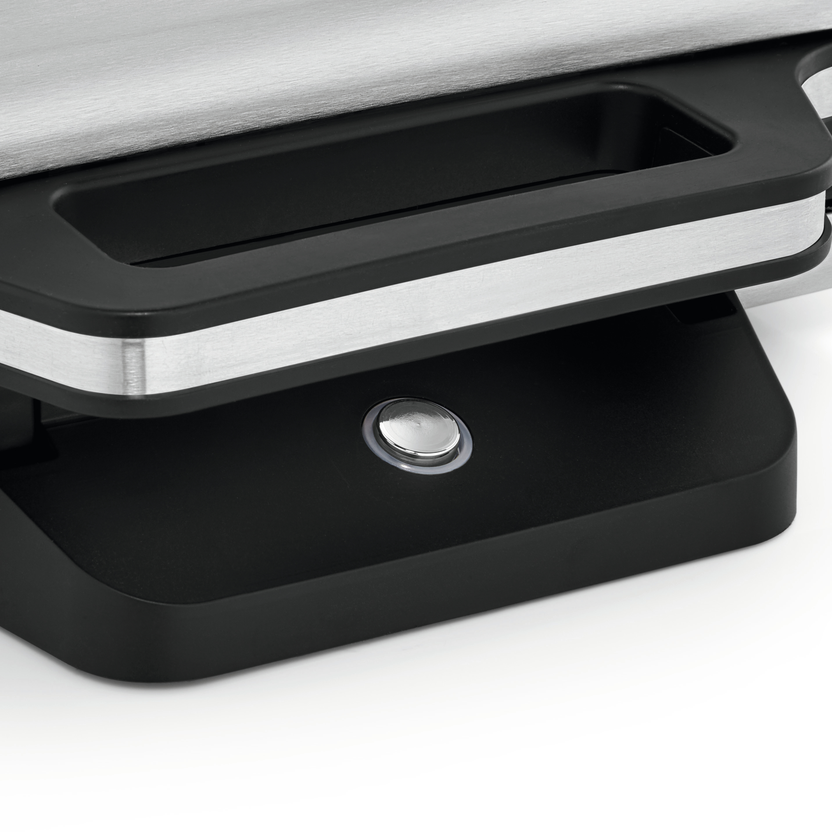 Zbliżenie srebrno-czarnego grilla. Widoczny uchwyt i przycisk.