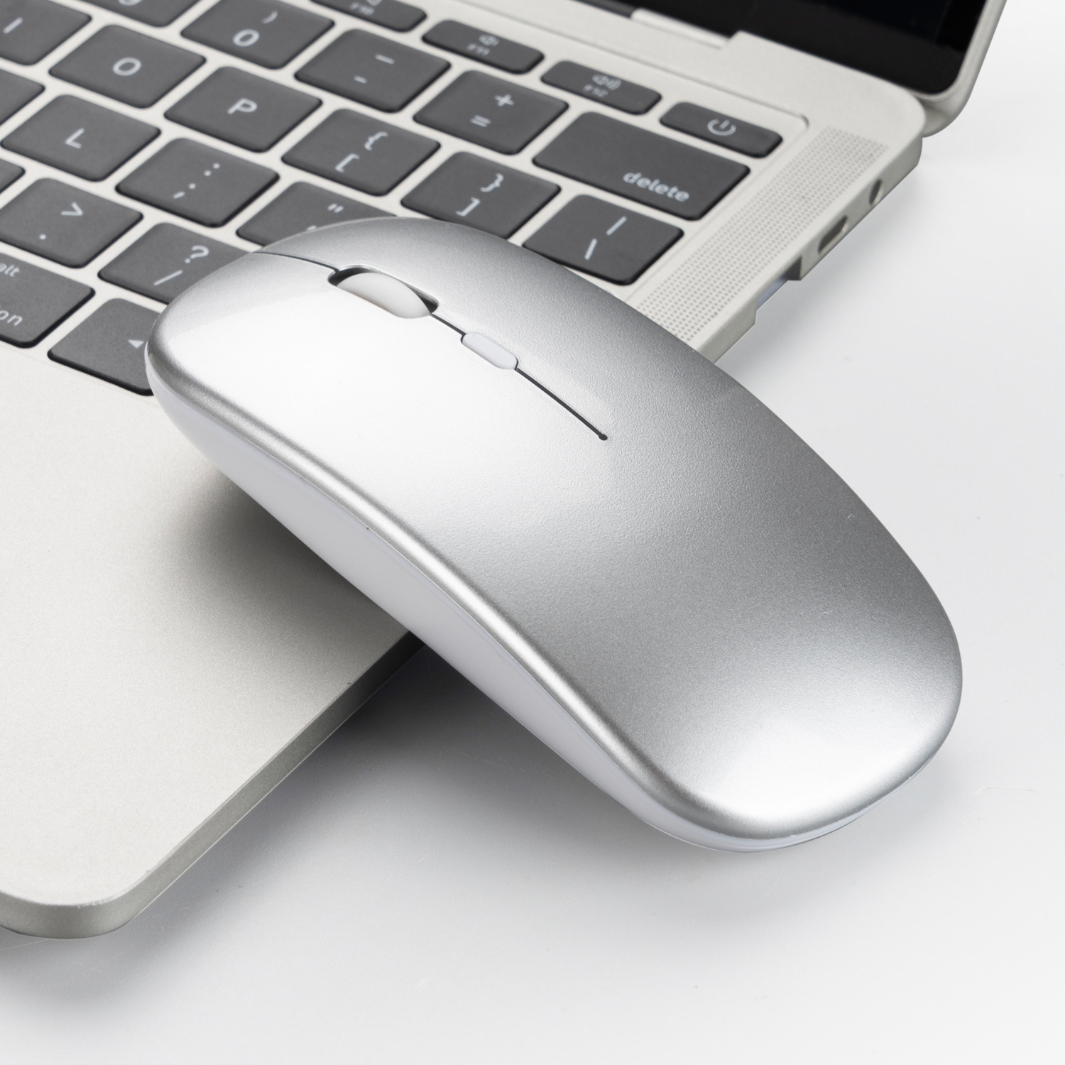 Un mouse argentato su un laptop. Il laptop è aperto, con una tastiera visibile.