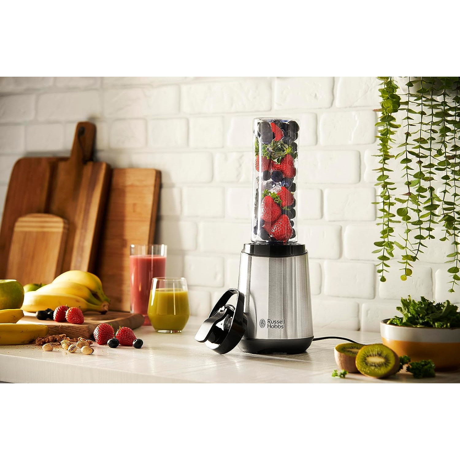 Mixer mit Früchten. Eine Küchenszene mit Obst und Grün.