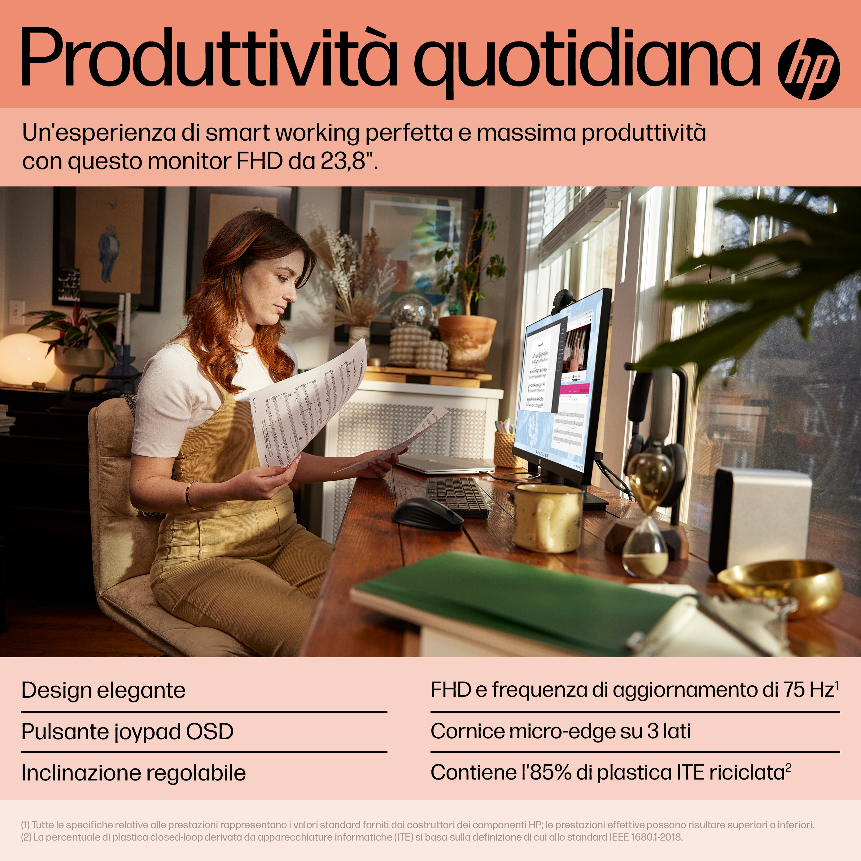 Una mujer sentada en un escritorio, trabajando con un monitor, sosteniendo un documento, con una lámpara de escritorio y una taza de café.