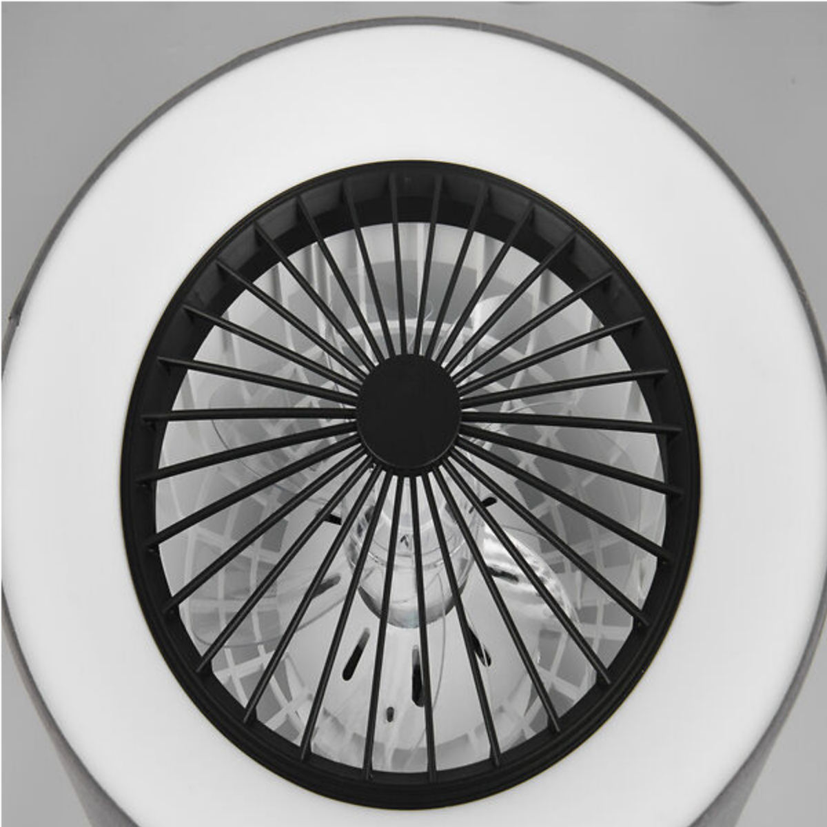 Primo piano di un ventilatore nero con gabbia metallica e luce bianca, visto dal basso.
