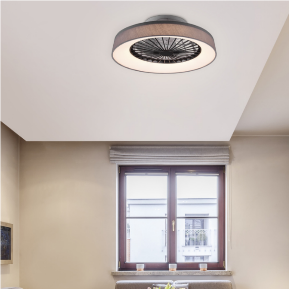 Ventilatore da soffitto con luce ad anello e copertura decorativa. È montato su un soffitto bianco.