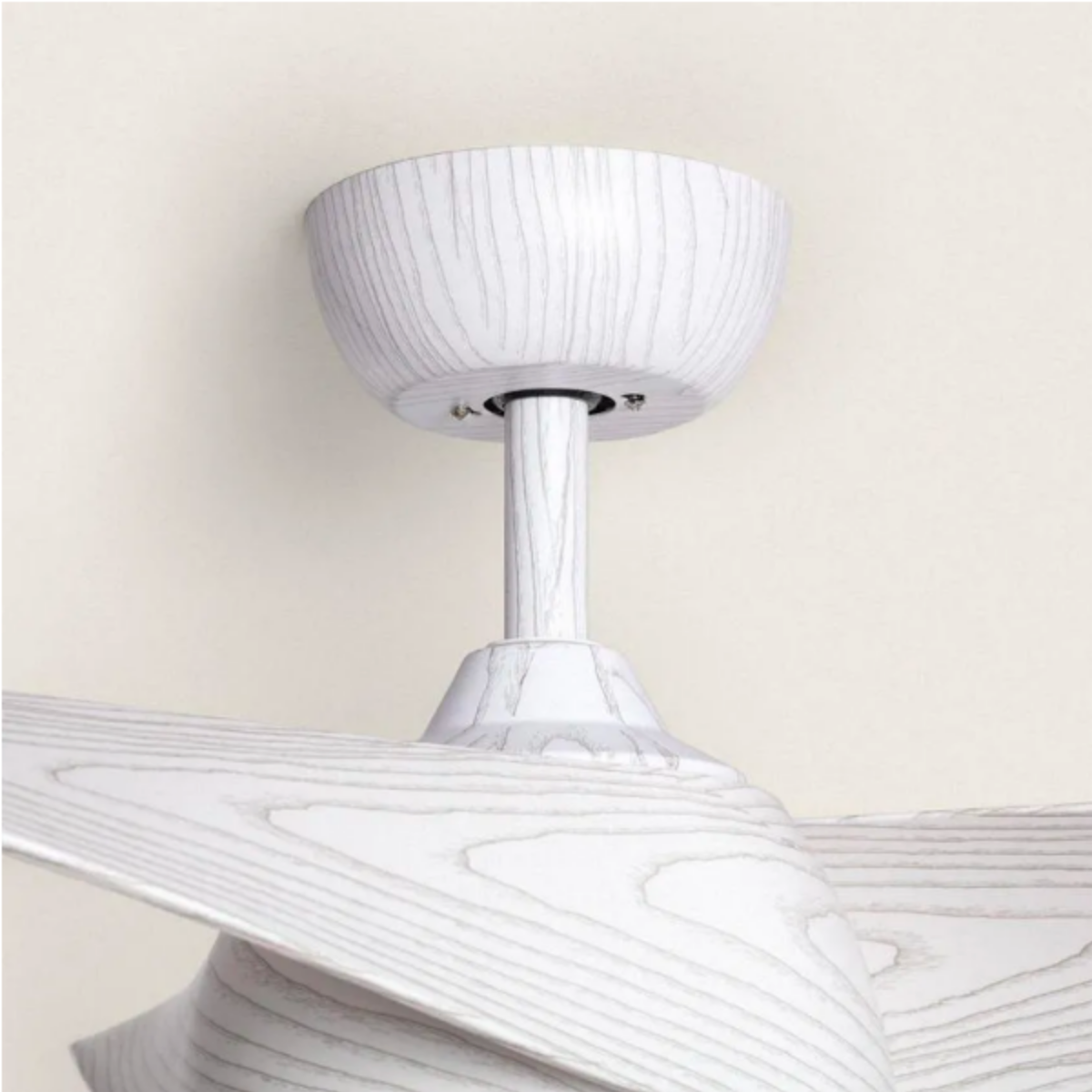 Primo piano di un ventilatore da soffitto bianco con finitura a venature del legno. Il ventilatore è montato su un soffitto beige.