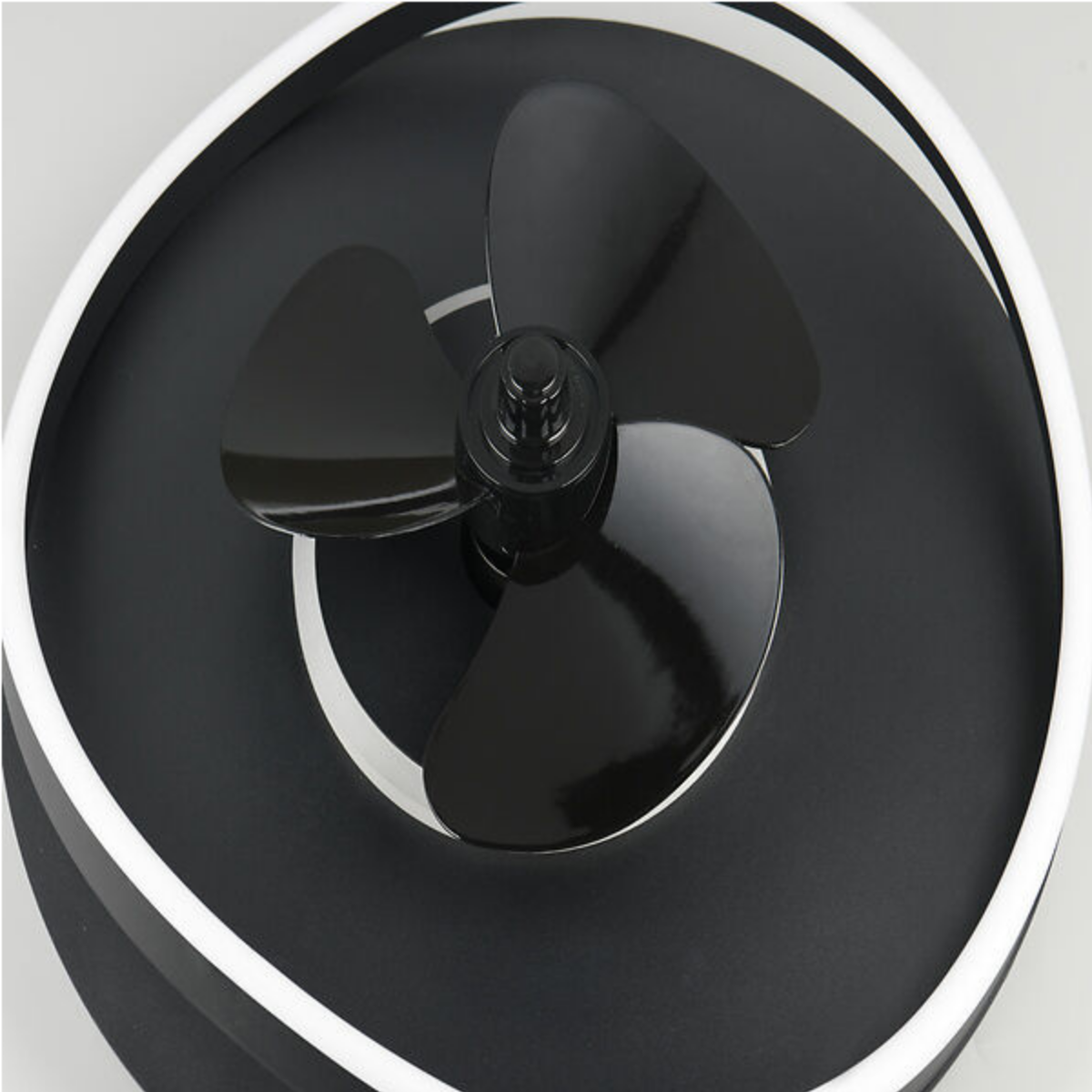 Una vista ravvicinata di un ventilatore da soffitto nero con tre pale e una luce bianca.