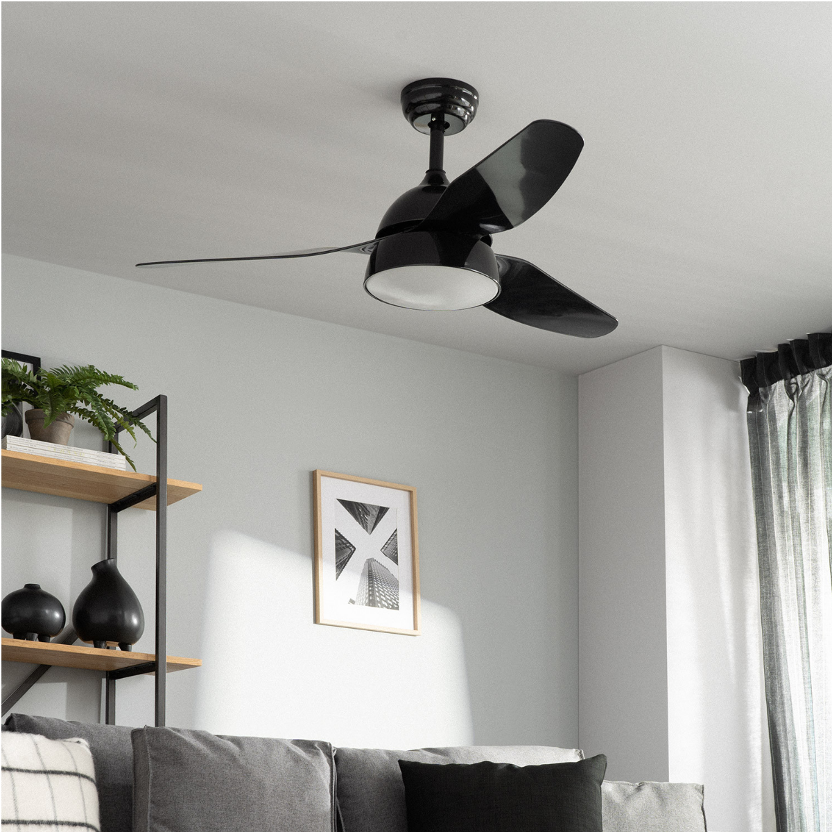 Un ventilatore da soffitto nero con tre pale è montato su un soffitto bianco.