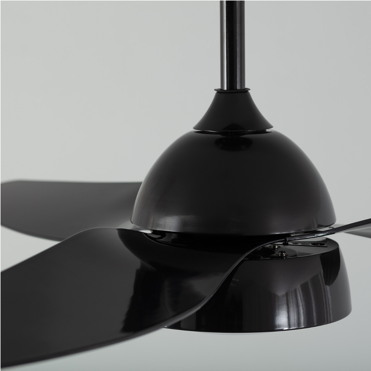 Primo piano di un ventilatore da soffitto nero, pale e base. Montato su un soffitto bianco.