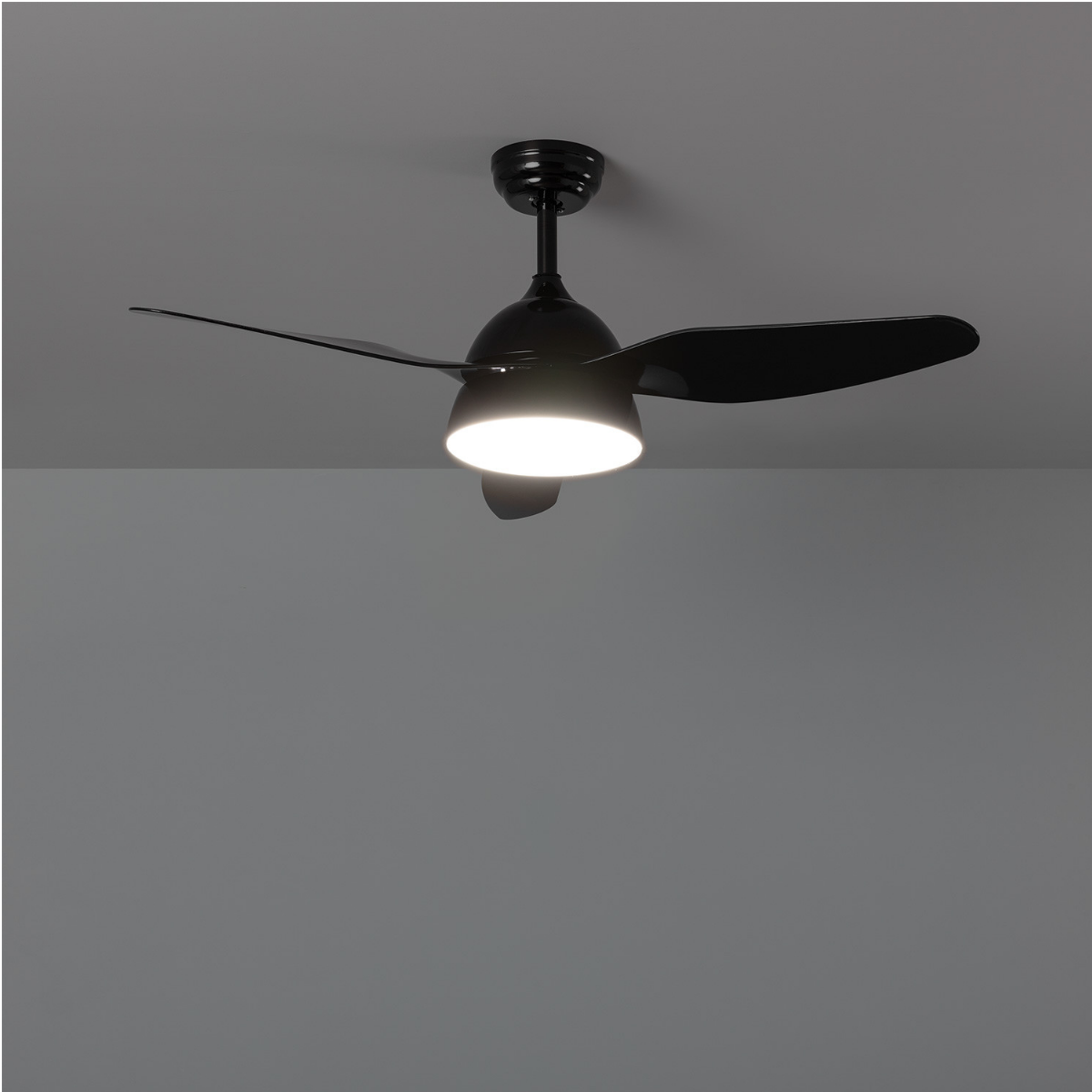 Un ventilatore a soffitto nero con luce visto dal basso.