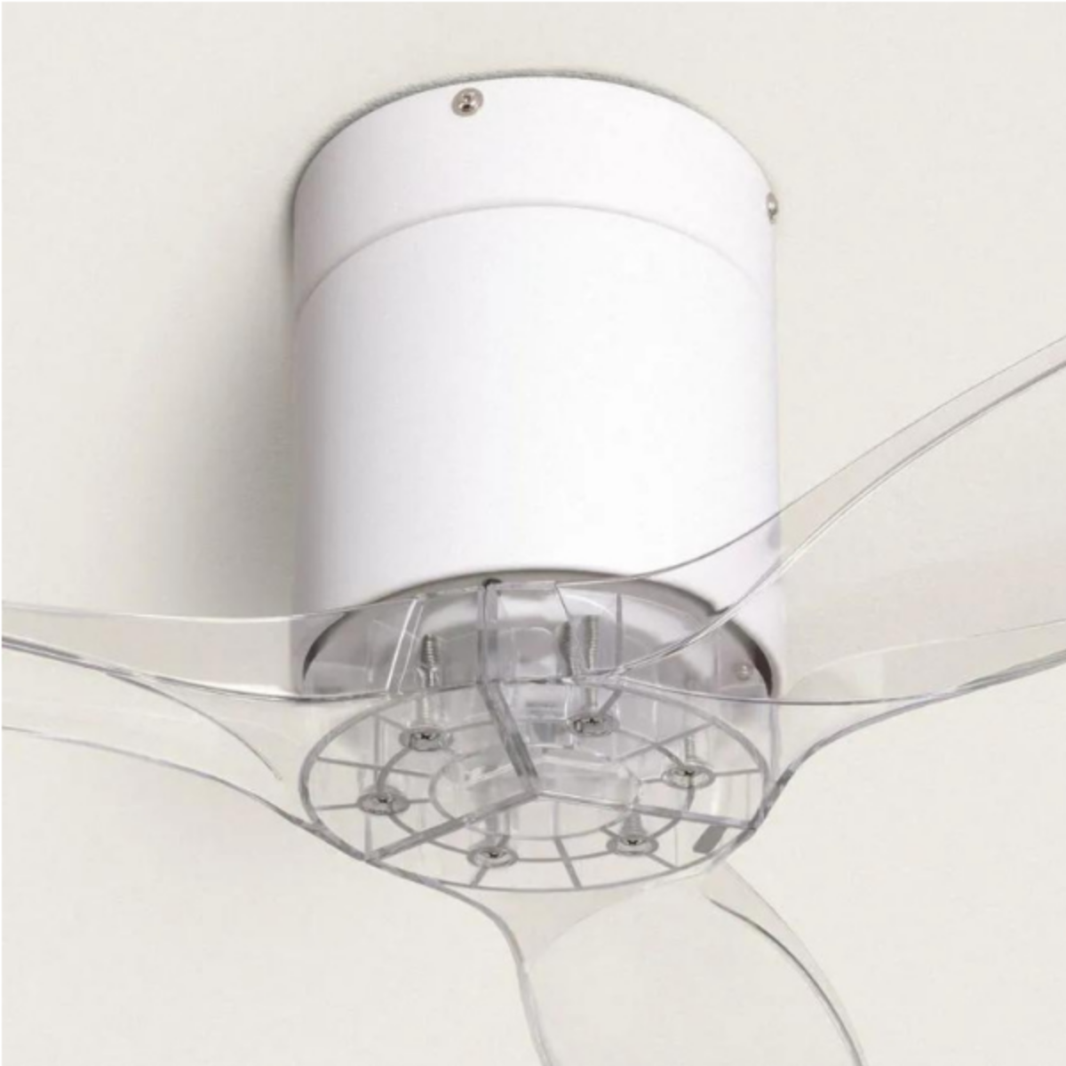 Primo piano di un ventilatore da soffitto bianco con pale trasparenti. Il ventilatore è montato su un soffitto bianco.