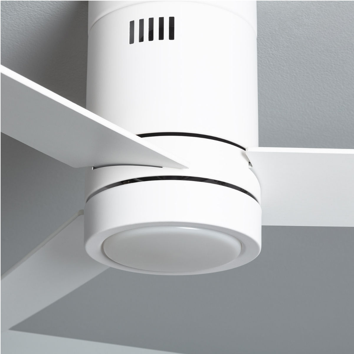 Primo piano di un ventilatore da soffitto bianco con quattro pale. Il ventilatore ha un'apparecchio di illuminazione.