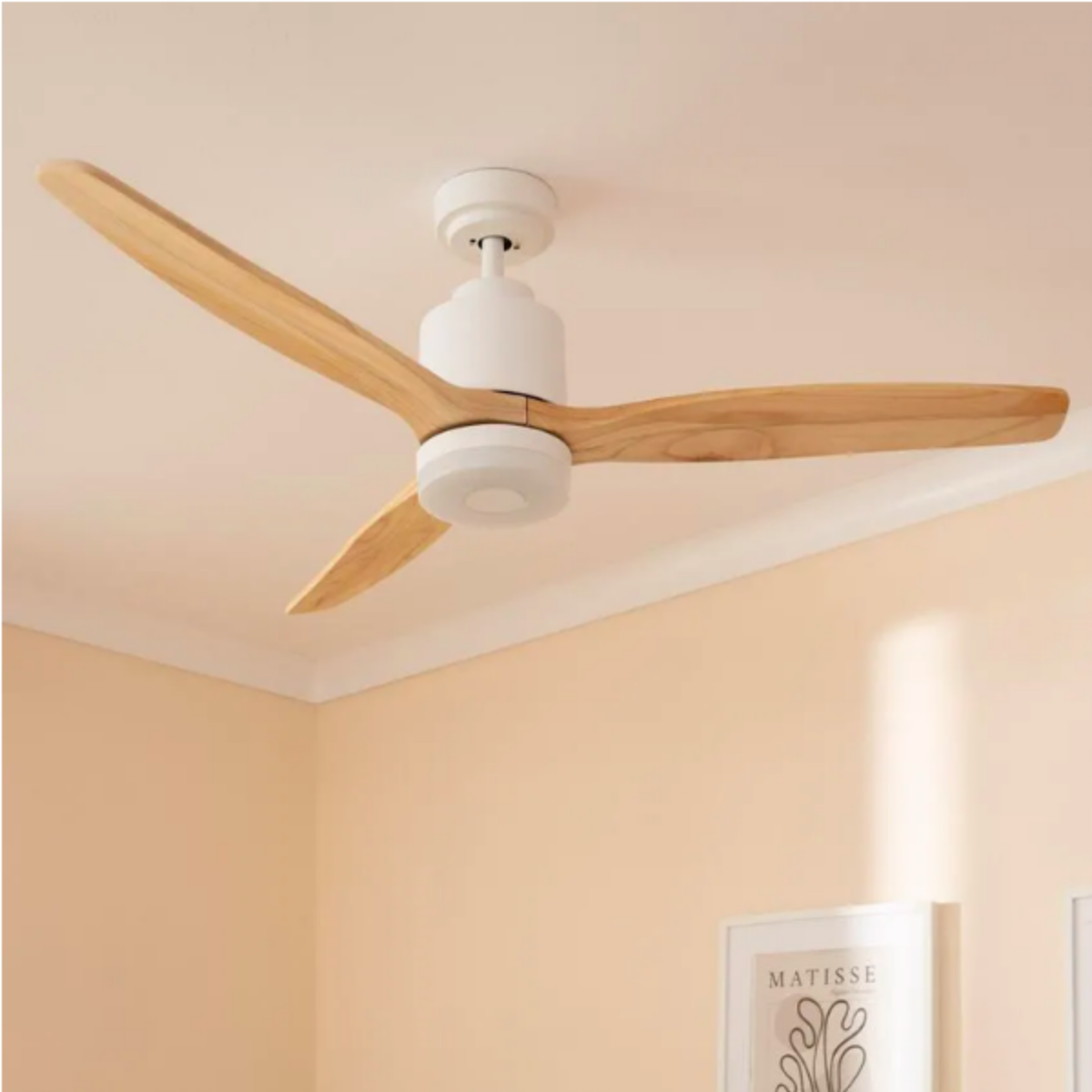 Ventilatore da soffitto bianco con pale in legno, montato su un soffitto beige in una stanza.