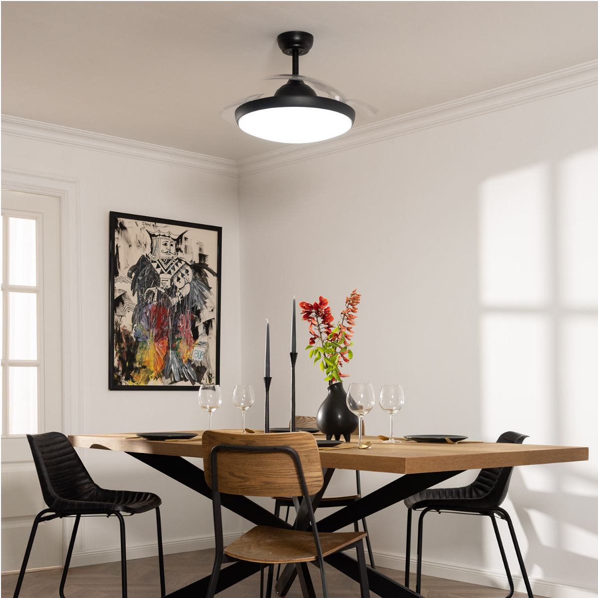 Una stanza con tavolo da pranzo, sedie, arte e ventilatore da soffitto nero con luce.