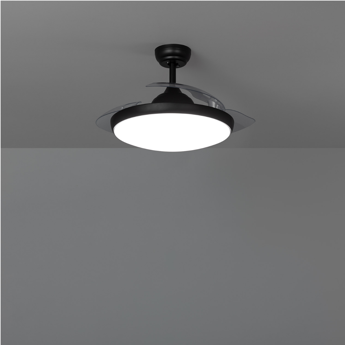 Un ventilatore a soffitto nero con luce visto dal basso su sfondo grigio.