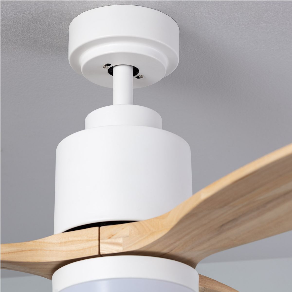 Primo piano del ventilatore da soffitto bianco, pale in legno e soffitto.