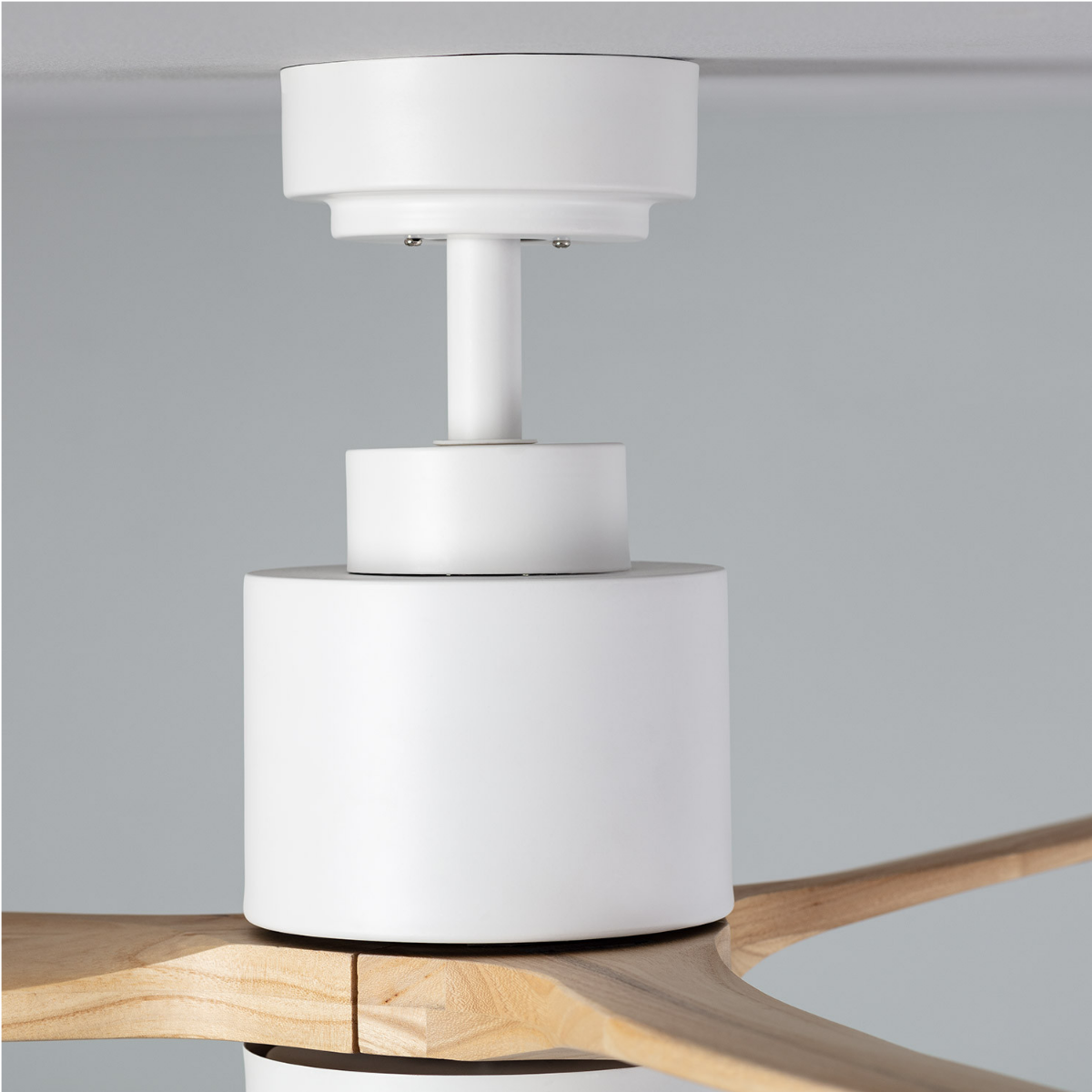 Primo piano del motore e delle pale di un ventilatore da soffitto bianco.