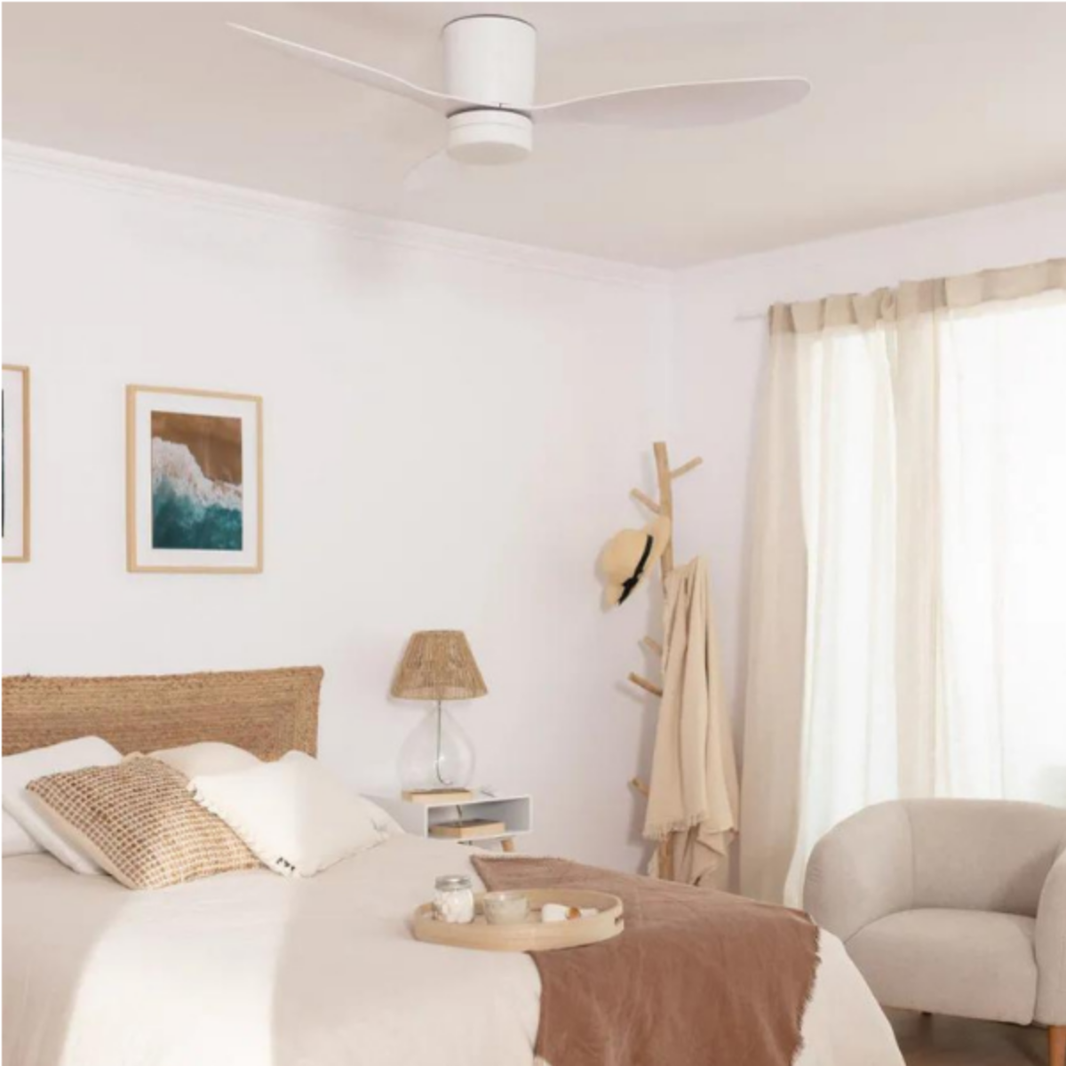 Un ventilatore da soffitto bianco con tre pale in una camera da letto. La stanza è luminosa.