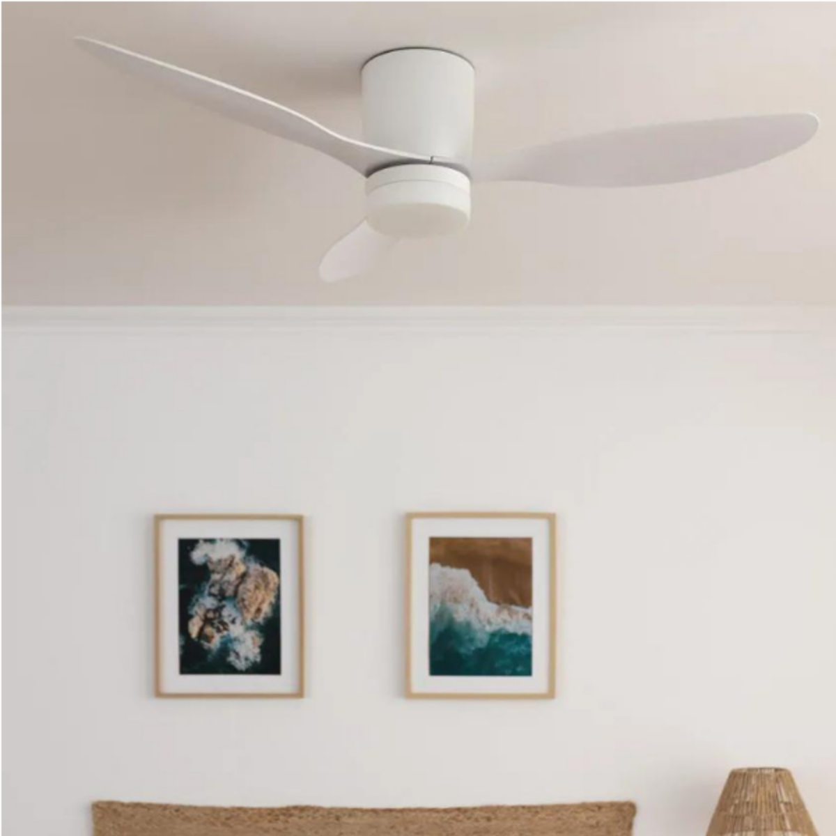 Ventilatore da soffitto bianco con due pale. Sfondo: due quadri incorniciati e un letto.