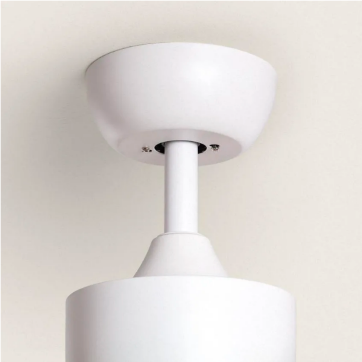 Primo piano dell'hardware di montaggio di un ventilatore da soffitto bianco contro un soffitto bianco.