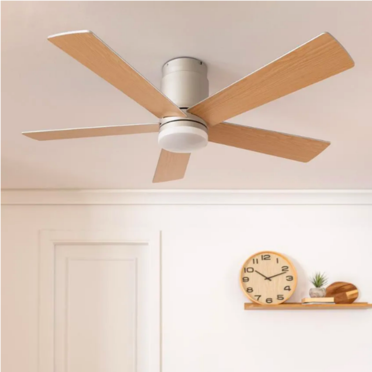 Ventilatore da soffitto con pale in legno in una stanza con orologio e arte sulla parete.