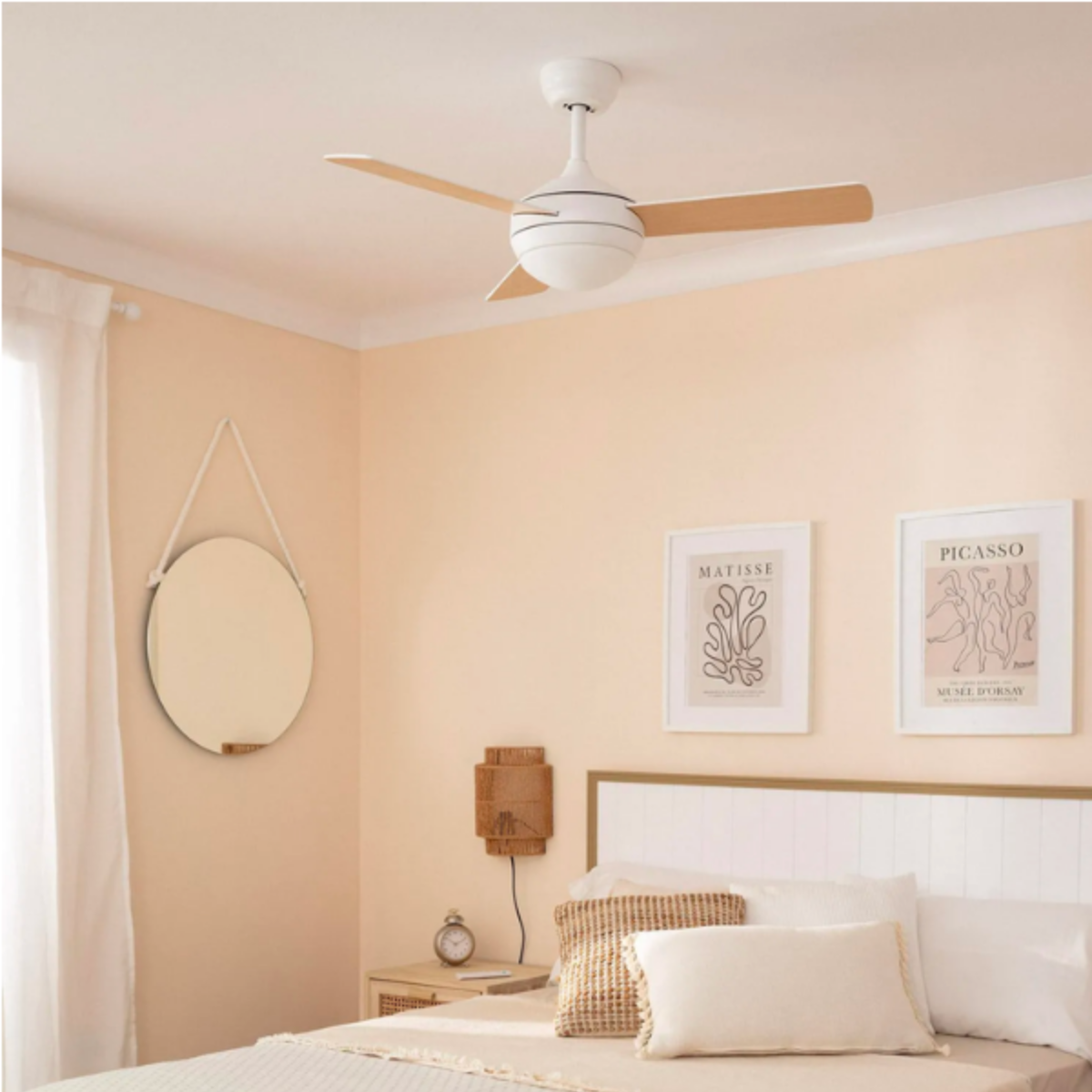 Un ventilatore da soffitto bianco con pale in legno in una camera da letto con parete color crema e specchio.