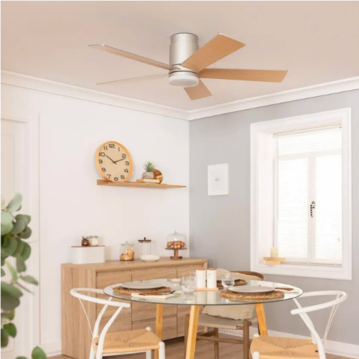 Una sala da pranzo con ventilatore a soffitto, tavolo in legno e orologio a parete.