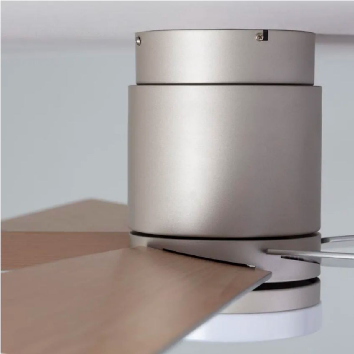 Primo piano di un motore di ventilatore da soffitto metallico e pale. Le pale sono in legno.