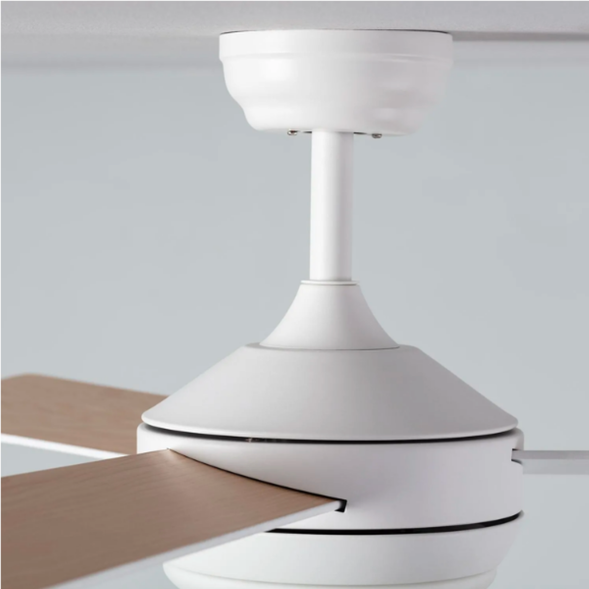 Primo piano di un ventilatore da soffitto bianco con pale in legno di colore chiaro.