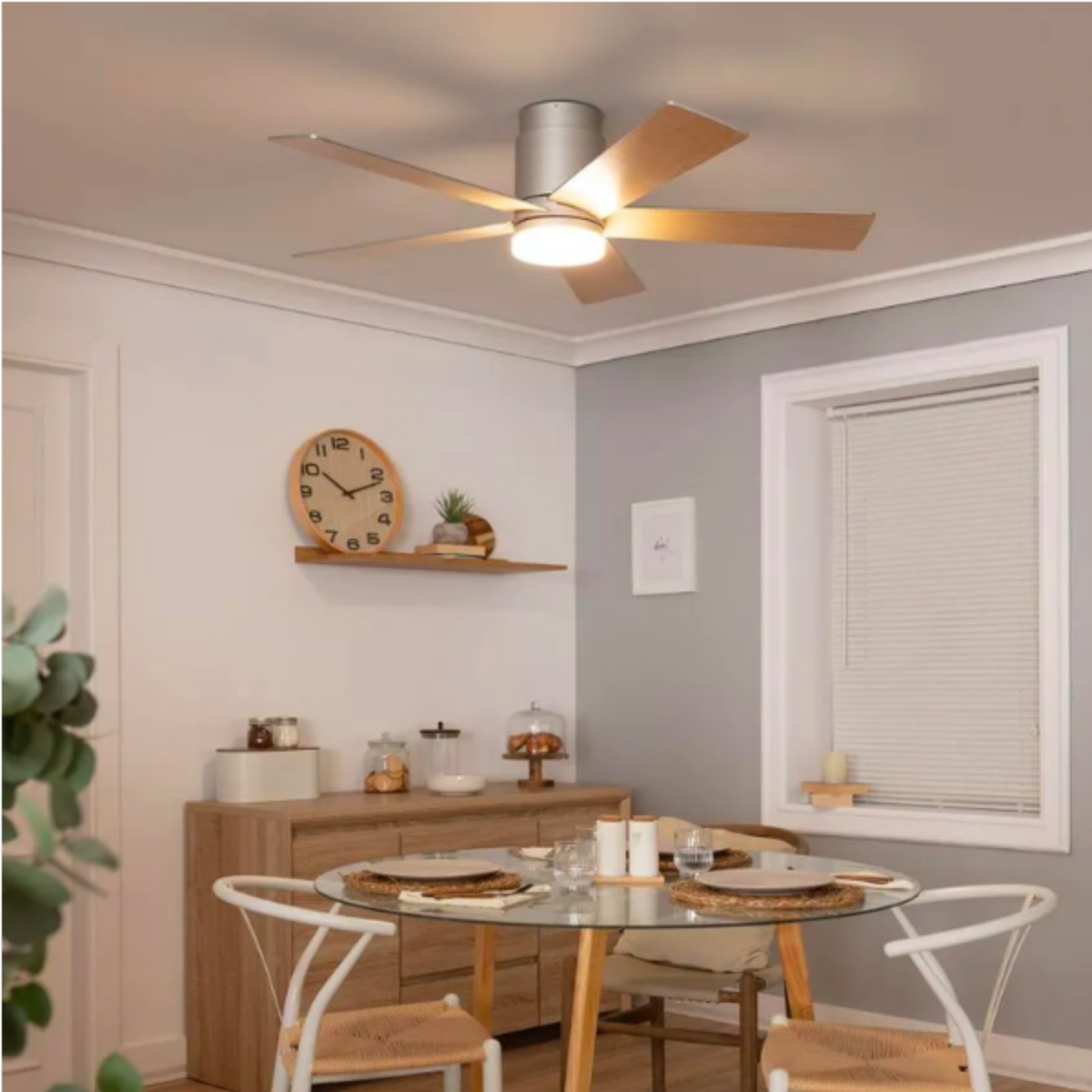 Una sala da pranzo con un ventilatore da soffitto. Include un orologio, arte e un tavolo di vetro.