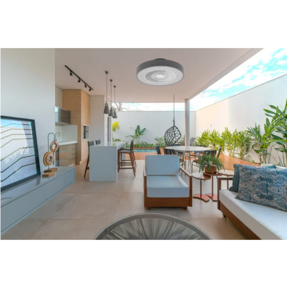 Area living all'aperto con ventilatore a soffitto, posti a sedere, zona pranzo e piscina sullo sfondo.