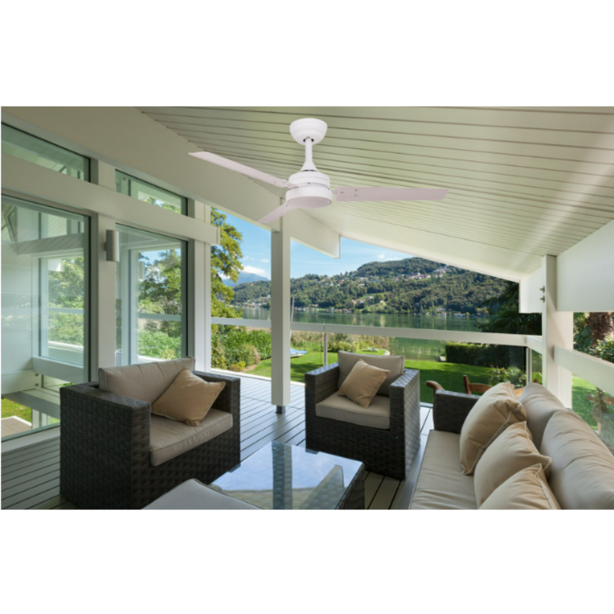 Un ventilatore a soffitto su un portico con vista su un lago. Due sedie e un divano sono sul portico.