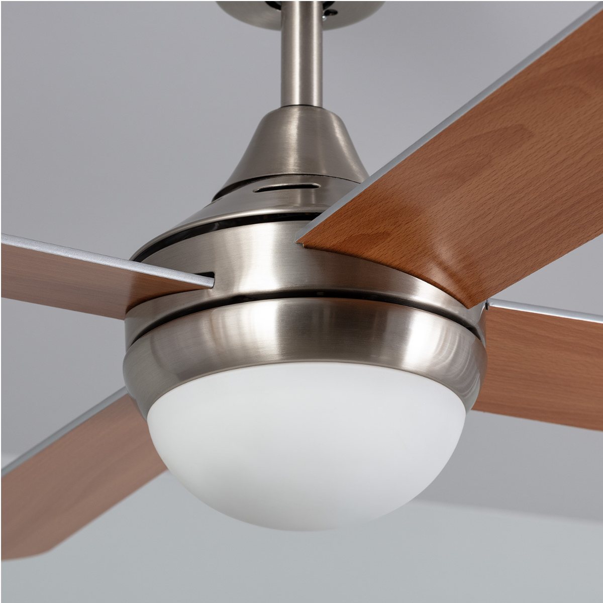 Un ventilatore a soffitto con pale in legno e una luce a globo bianca. Lo sfondo è grigio.