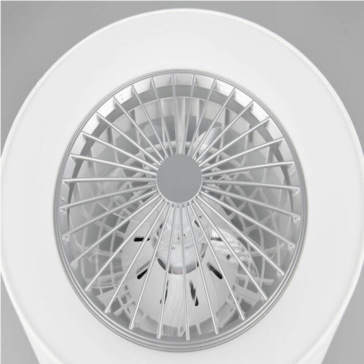 Primo piano di un ventilatore a soffitto con metallo argentato e un anello esterno bianco.