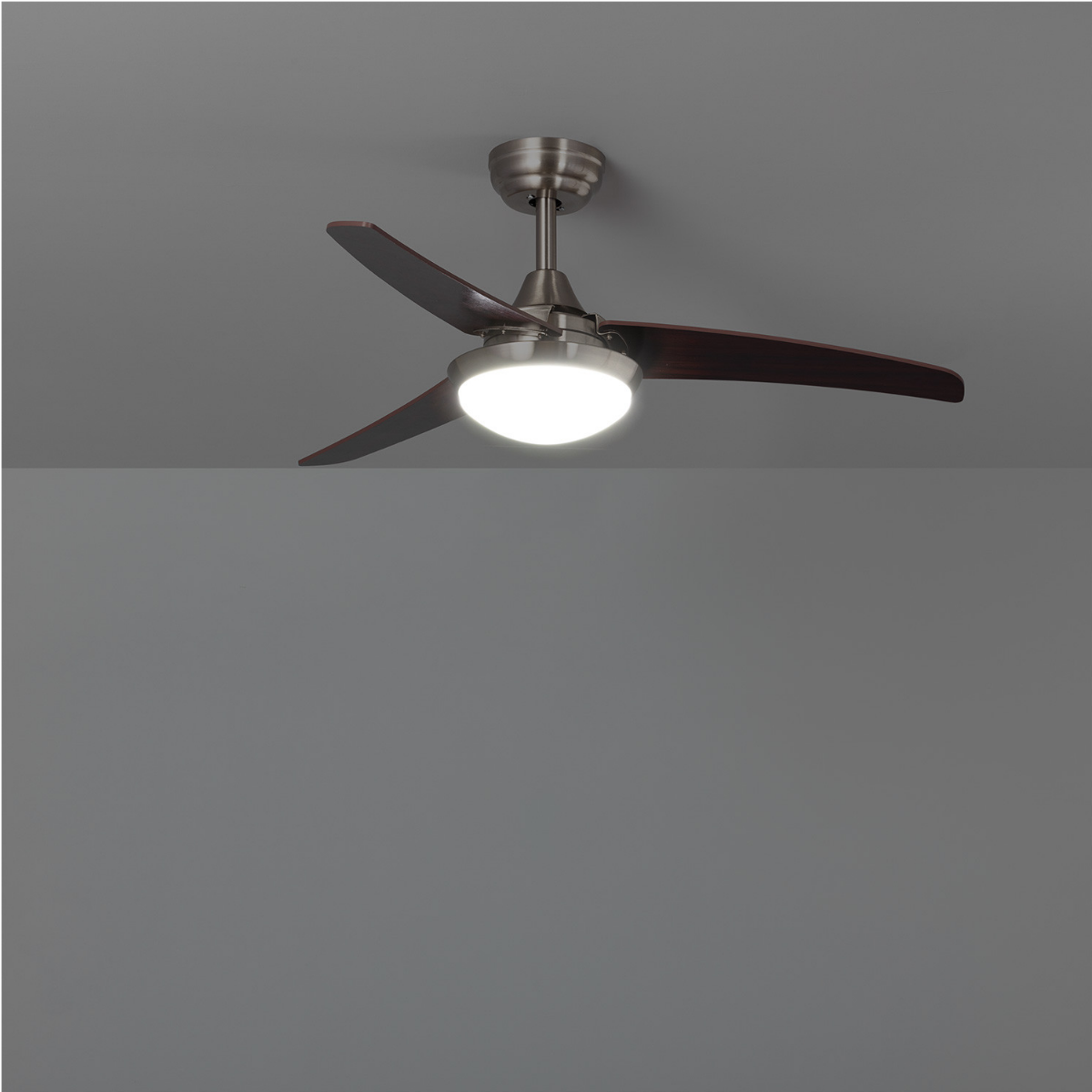 Ventilatore a soffitto con pale in legno scuro e luce centrale, contro soffitto grigio.