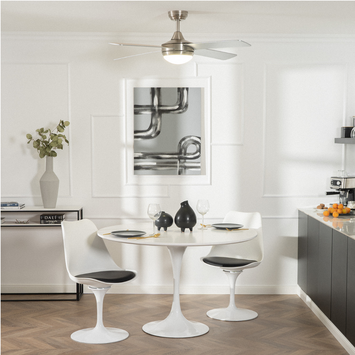 Una cucina con ventilatore a soffitto, tavolo con sedie e un quadro.