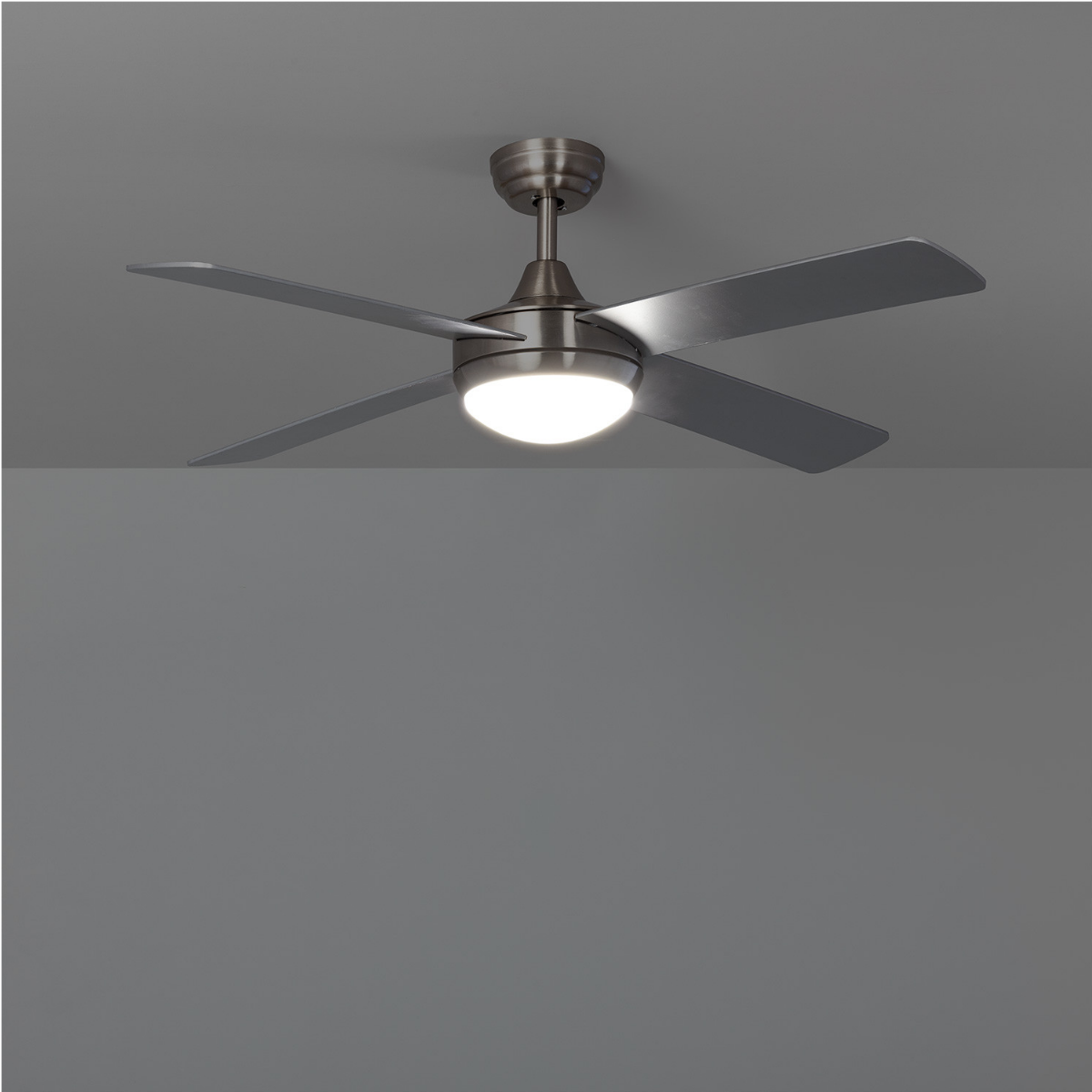Ventilatore a soffitto con quattro pale e una luce su sfondo grigio.