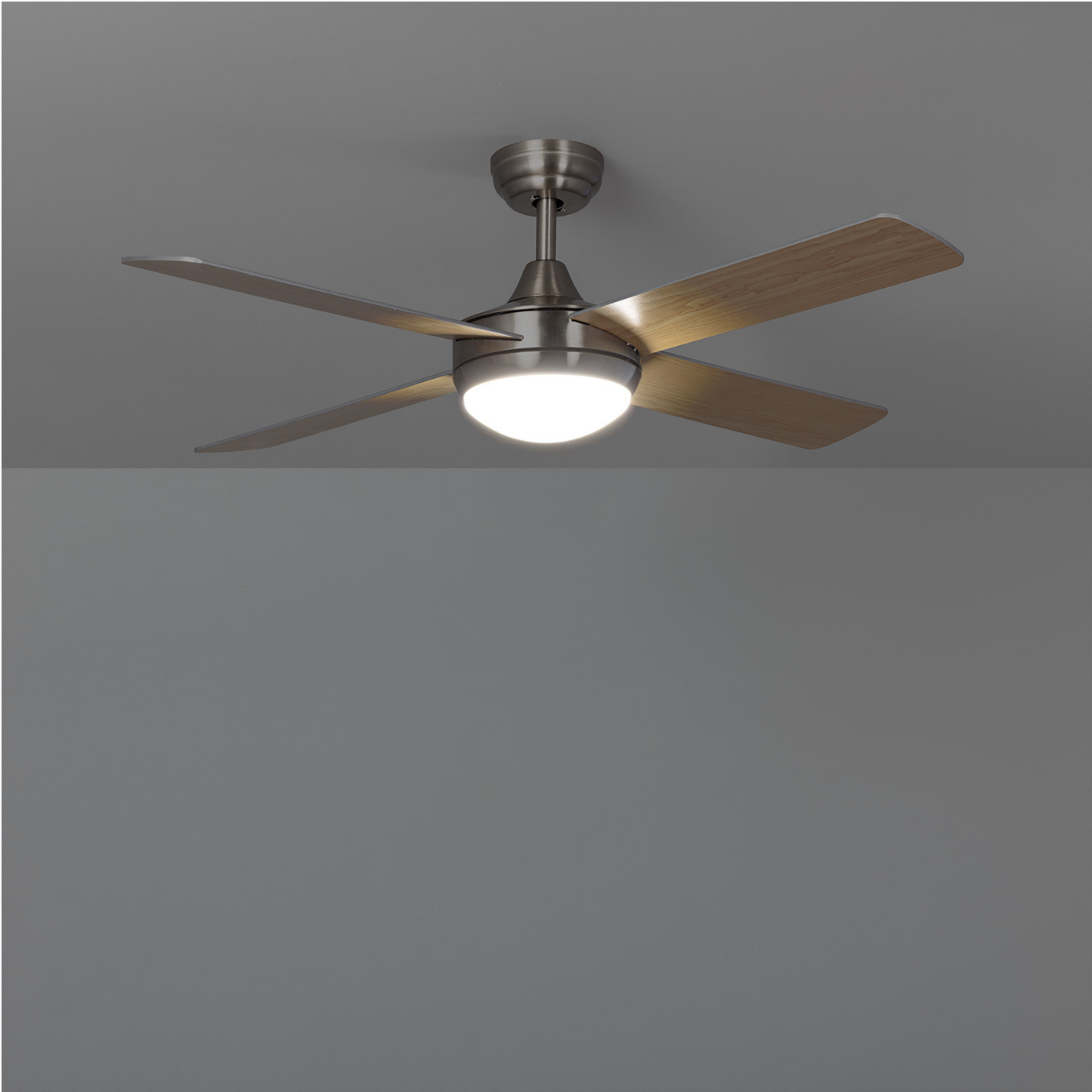 Ventilatore da soffitto con quattro pale e una luce. Lo sfondo è grigio uniforme.