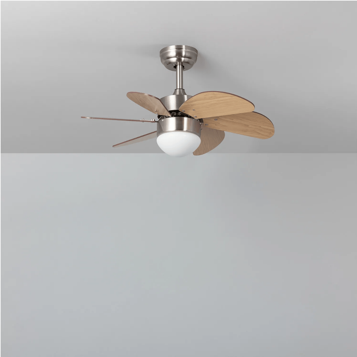 Ventilatore a soffitto con sei pale in legno contro soffitto grigio.