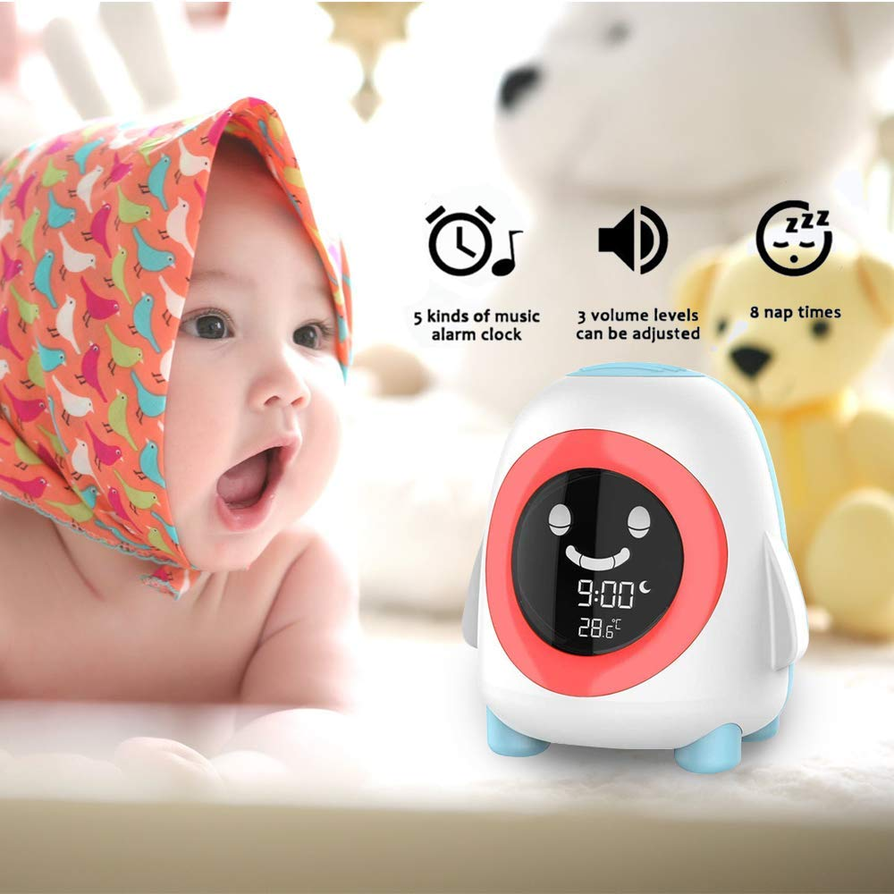 Baby mit Kopftuch und einem pinguinförmigen Wecker.