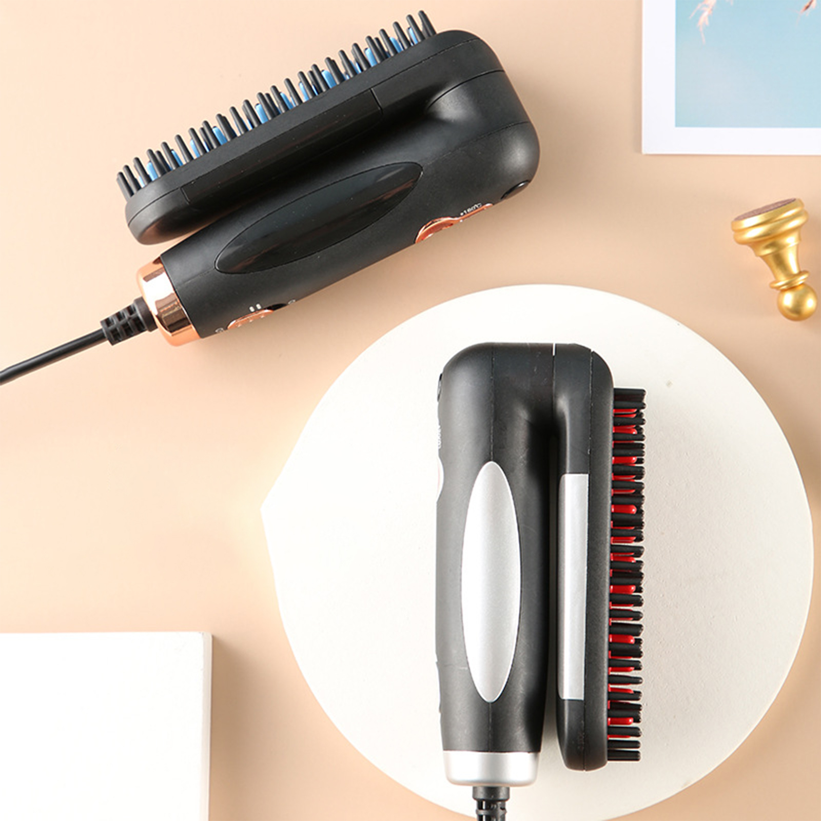 Schwarze und goldene Haarstyling-Werkzeuge. Eins wird benutzt, mit schwarzen und blauen Borsten, das andere auf einem Teller.