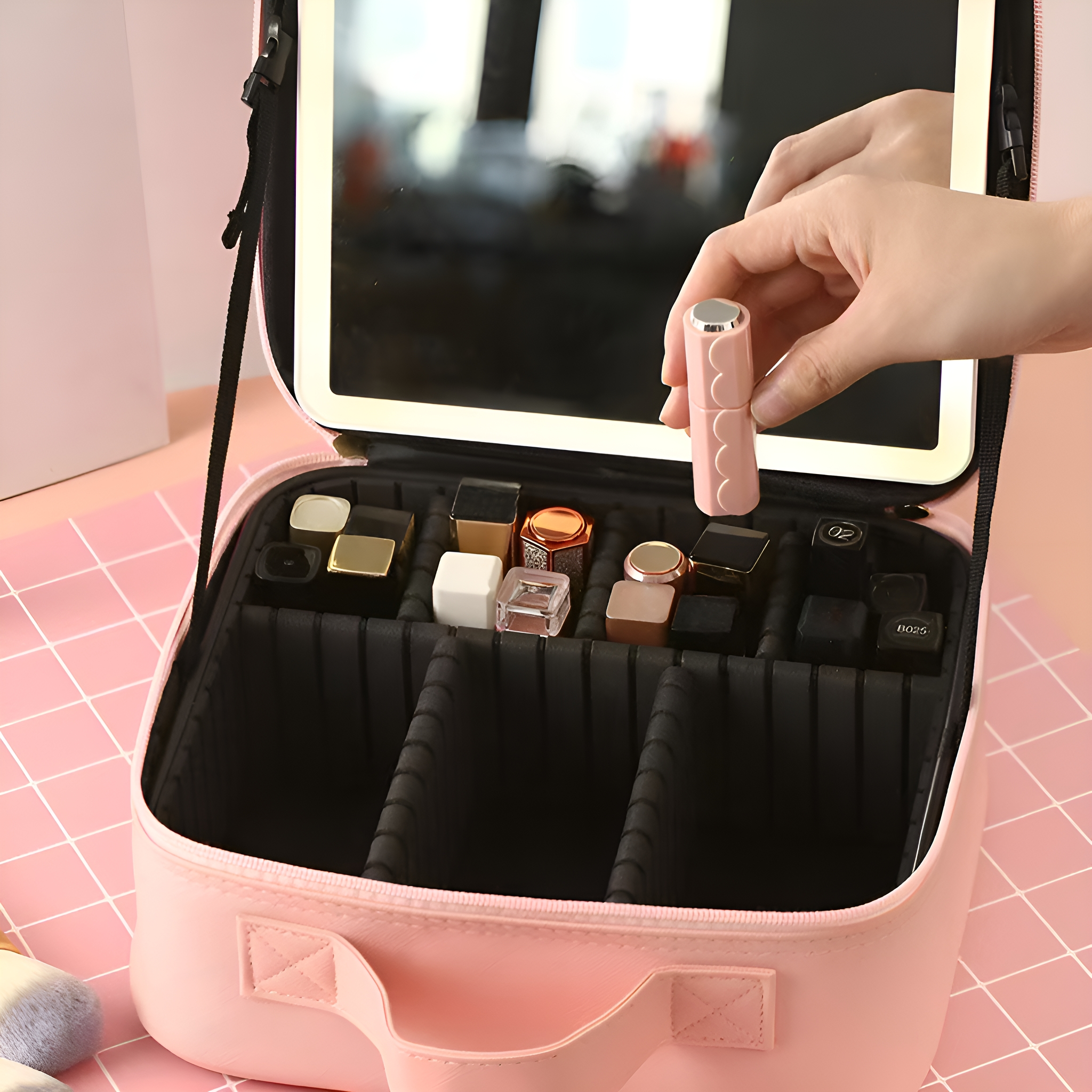 Eine rosa Make-up-Tasche mit Spiegel und verschiedenen Kosmetika. Eine Hand hält einen Lippenstift.
