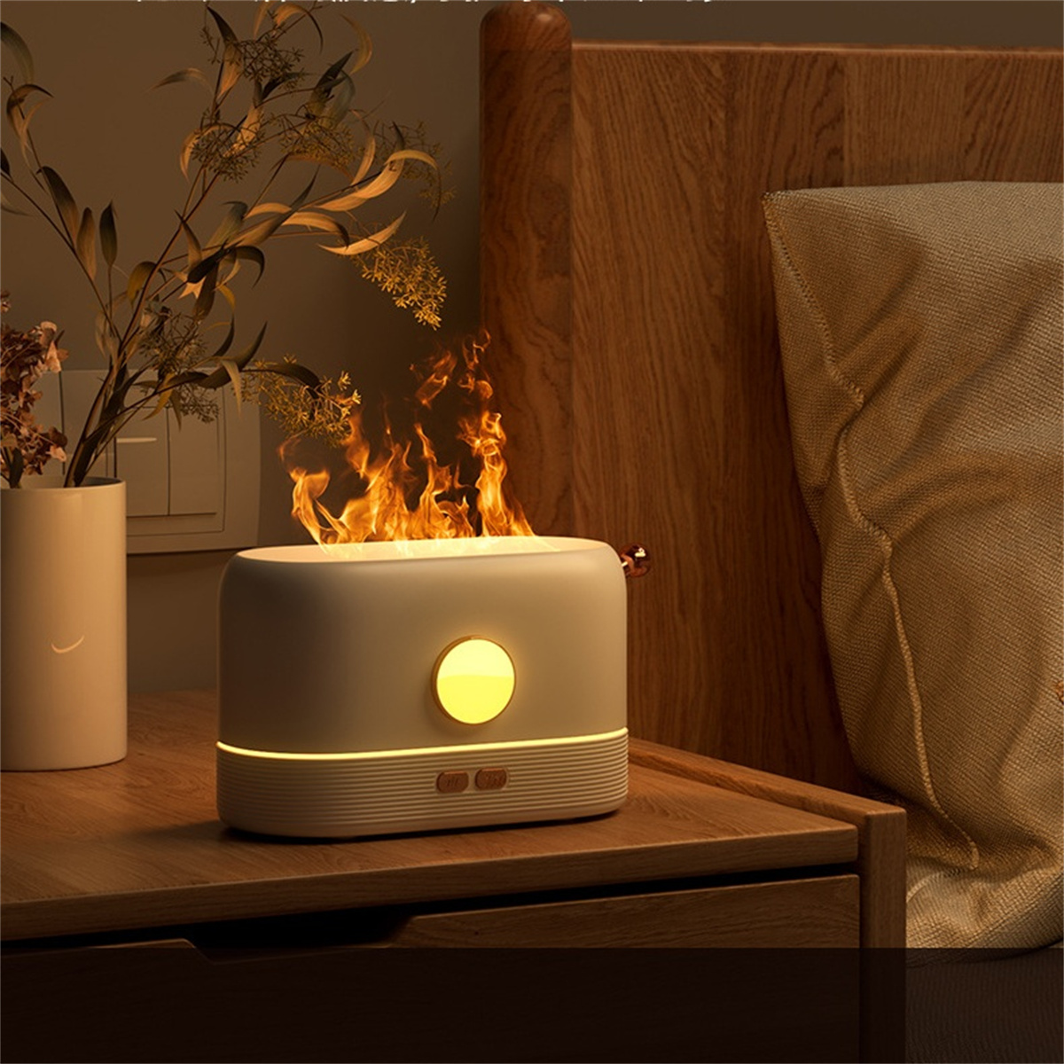 Weiß-grauer Flammendiffusor. Oben befindet sich ein flammenartiger Effekt. Es steht auf einem Nachttisch.