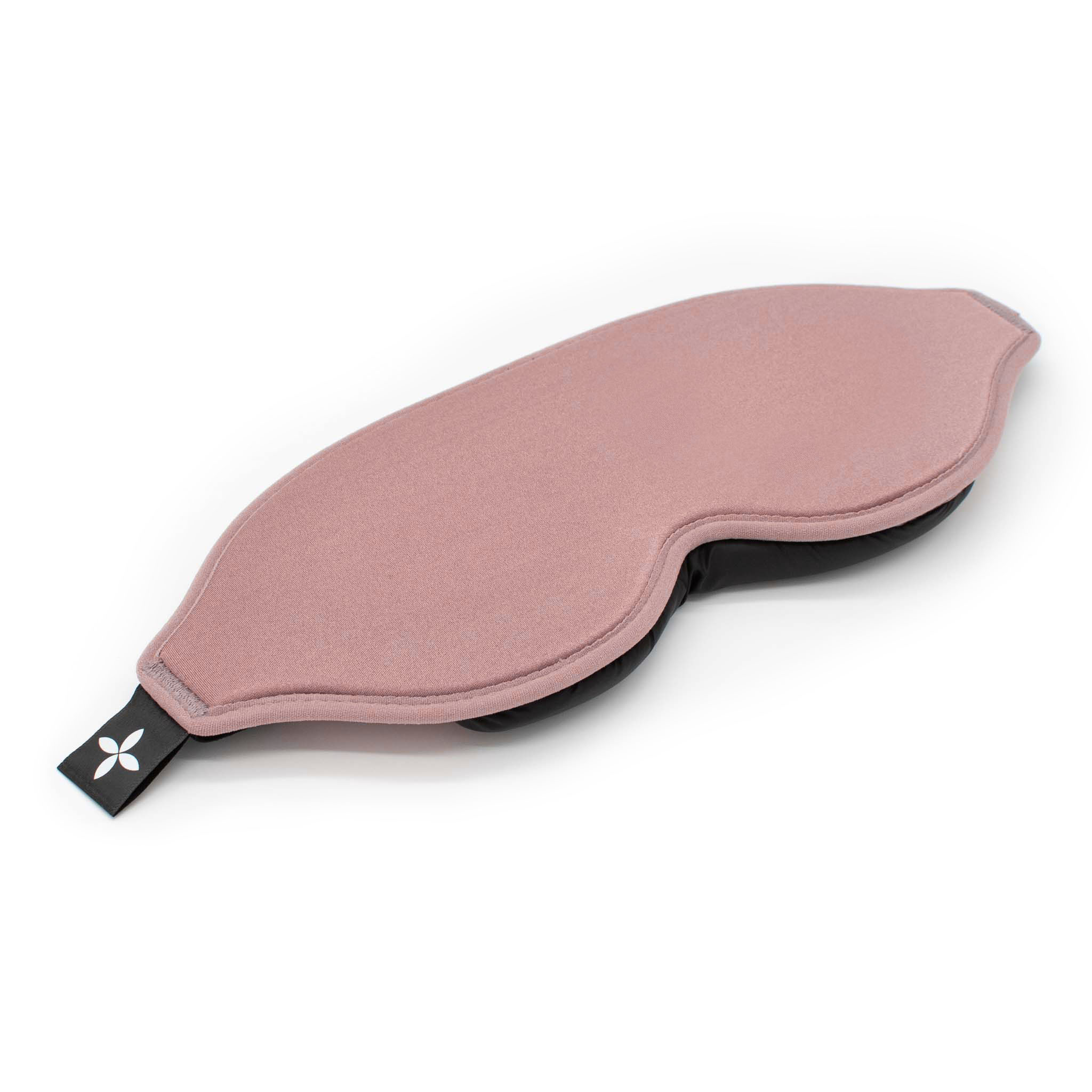 Eine rosa Schlafmaske liegt flach auf weißem Untergrund. Sie hat ein schwarzes Band mit Logo.