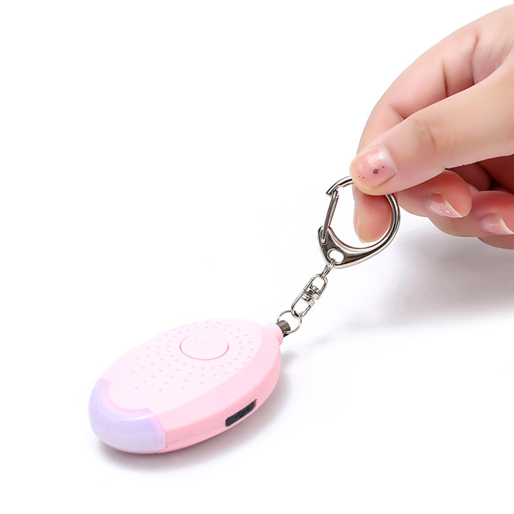 Ein rosa Schlüsselanhänger-Alarm, der von einer Hand auf weißem Hintergrund gehalten wird.